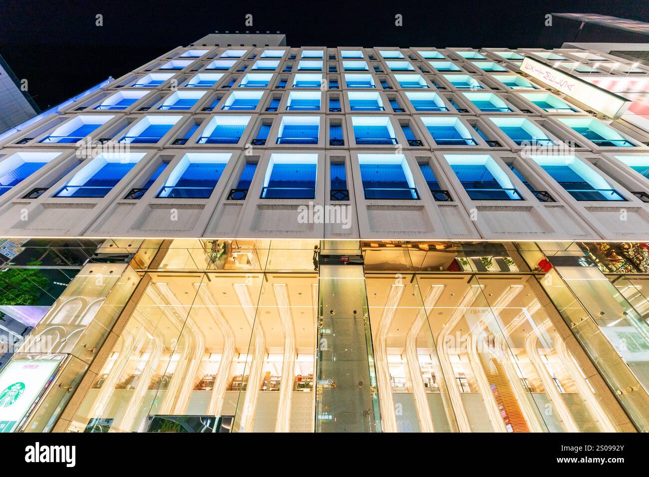 Das Exitmelsa Einkaufszentrum auf der Ginza bei Nacht. Niedriger Blickwinkel bei Nacht direkt nach oben auf die blau beleuchteten Fenster. Stockfoto