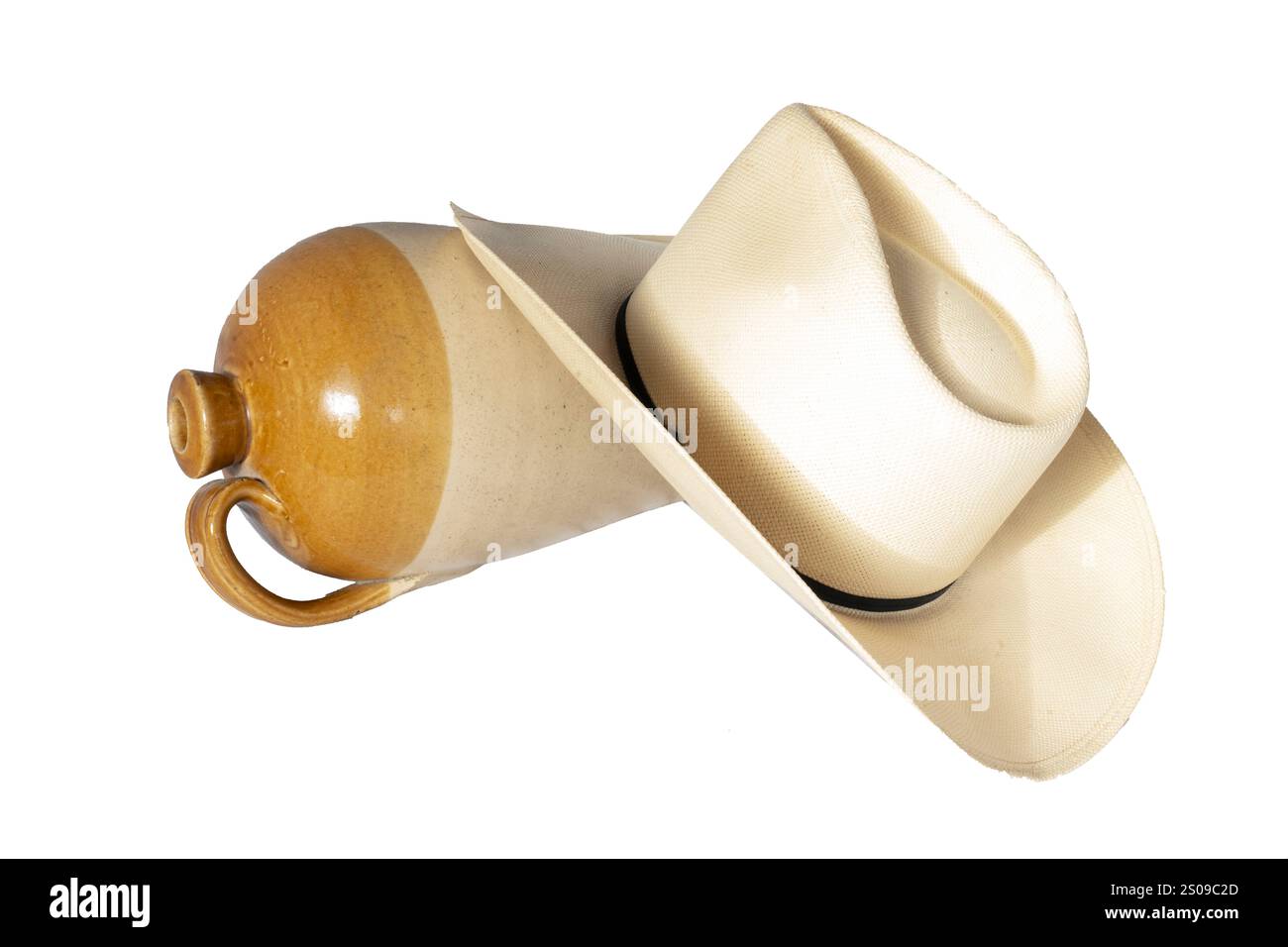 Isolierter Cowboyhut mit leerem alten Keramikkrug auf der Seite zeigt westliches Casual Living oder alte Westidee der Dude Ranch. Der Hut liegt auf dem Boden. Stockfoto