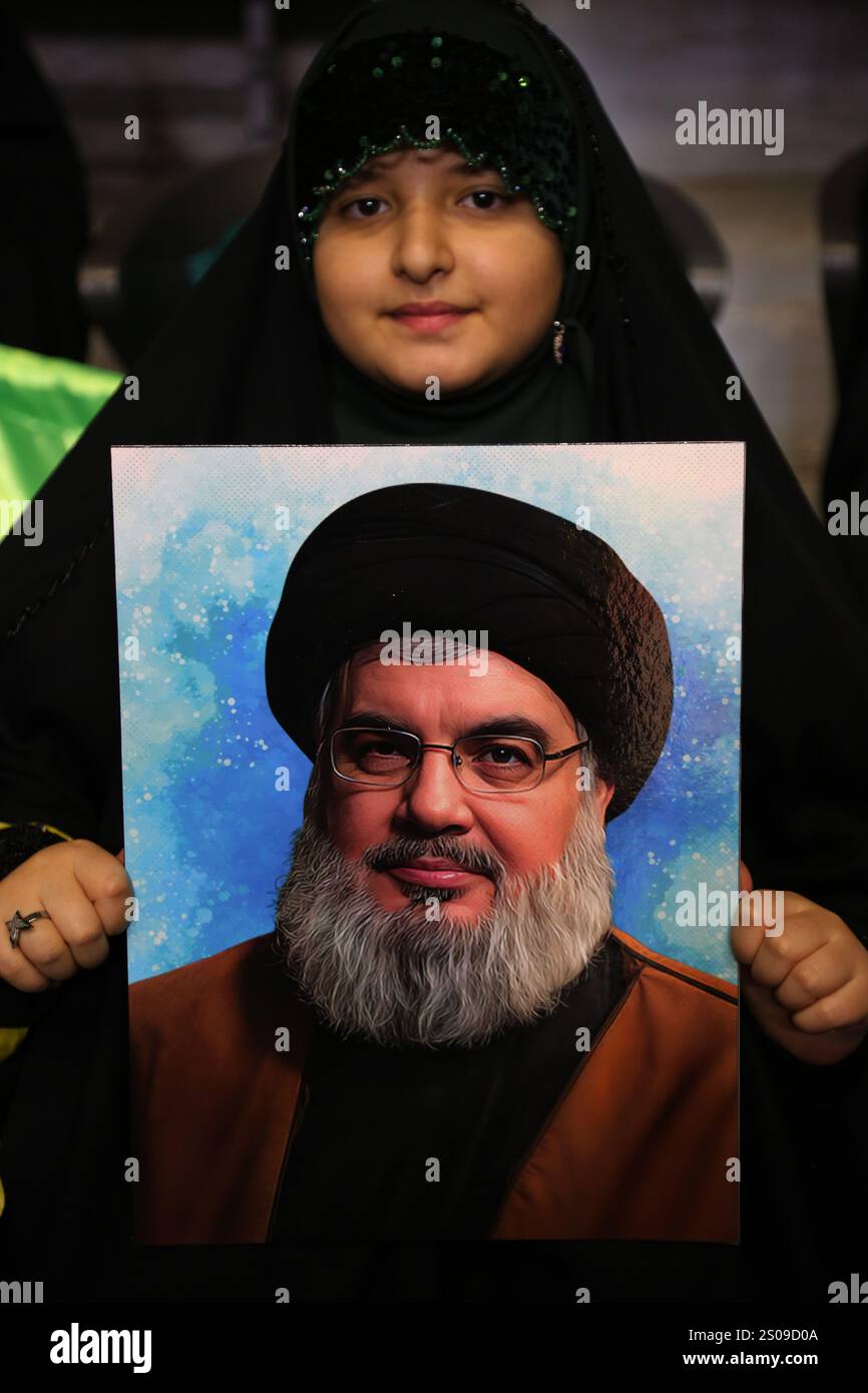 Teheran, Iran. Dezember 2024. Ein iranisches junges verschleiertes Mädchen trägt ein Porträt des verstorbenen Anführers der militanten Hisbollah-Gruppe im Libanon, Hassan Nasrallah, während einer Zeremonie zum Jahrestag des Todes von Generalmajor Qasem Soleimani, der am 3. Januar 2020 bei einem US-Drohnenangriff in Bagdad im Azadi Indoor Stadium im Westen Teherans getötet wurde. (Kreditbild: © Rouzbeh Fouladi/ZUMA Press Wire) NUR REDAKTIONELLE VERWENDUNG! Nicht für kommerzielle ZWECKE! Stockfoto