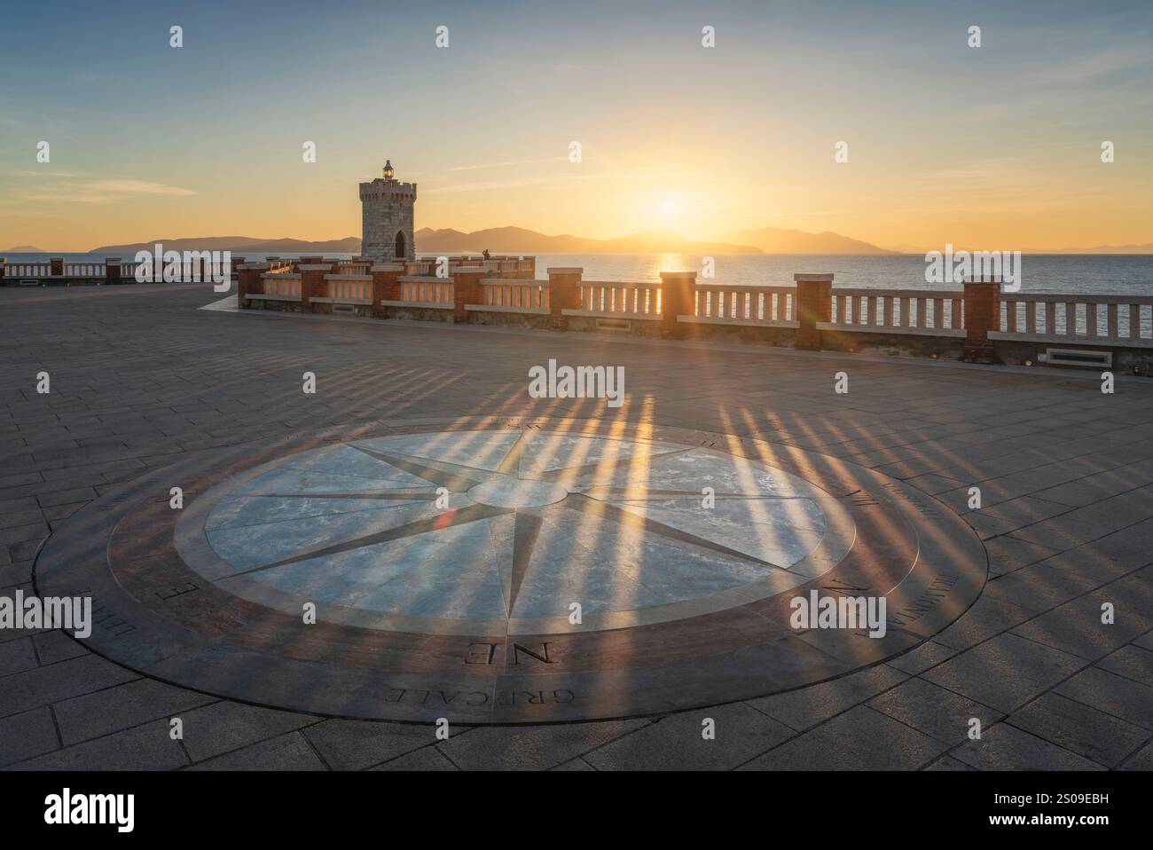 Piombino, Blick auf die Windrose der Piazza Bovio und den Leuchtturm bei Sonnenuntergang, Insel Elba im Hintergrund. Maremma, Provinz Livorno, toskanische Region, Stockfoto