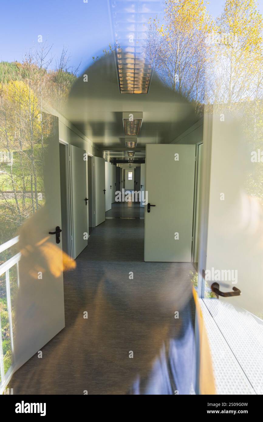Korridorblick mit Türen und Fenstern, im Glas sichtbare Reflexion der Natur, Flüchtlingsunterkunft Beermiss, Calmbach, Schwarzwald, Deutschland, Euro Stockfoto