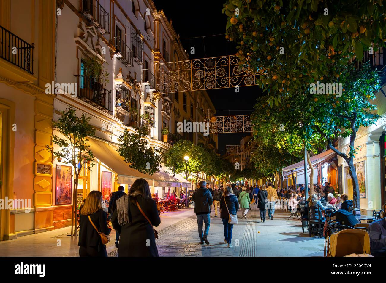 Abends können Sie in den beleuchteten Straßencafés im touristischen Viertel Barrio Santa Cruz der andalusischen Stadt Sevilla, Spanien, speisen. Stockfoto