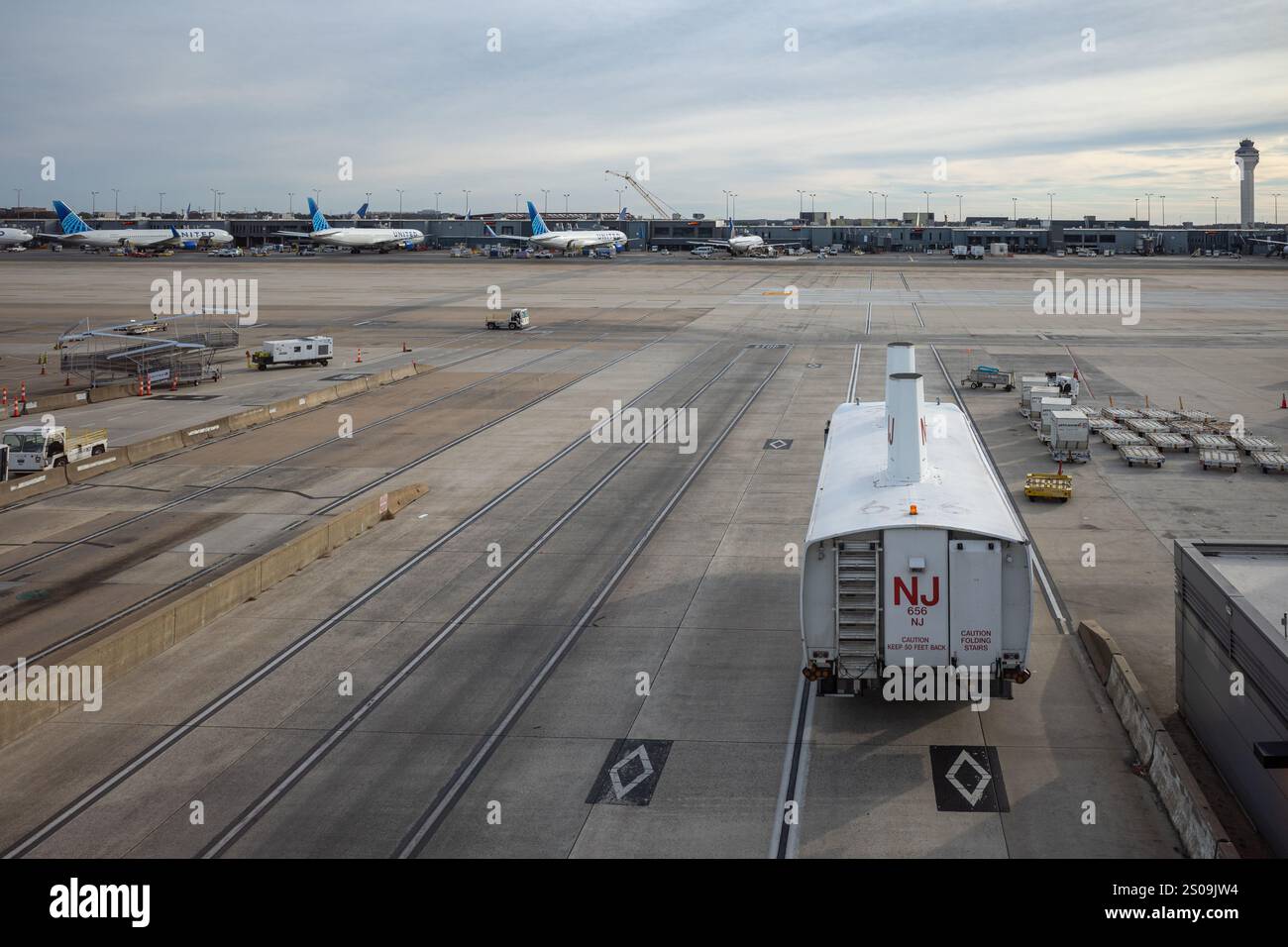 Eine geschäftige Szene am Flughafen Dulles, Washington, mit Bussen, die zwischen Terminals verkehren, eingerahmt vom Kontrollturm und geerdeten Flugzeugen. Stockfoto