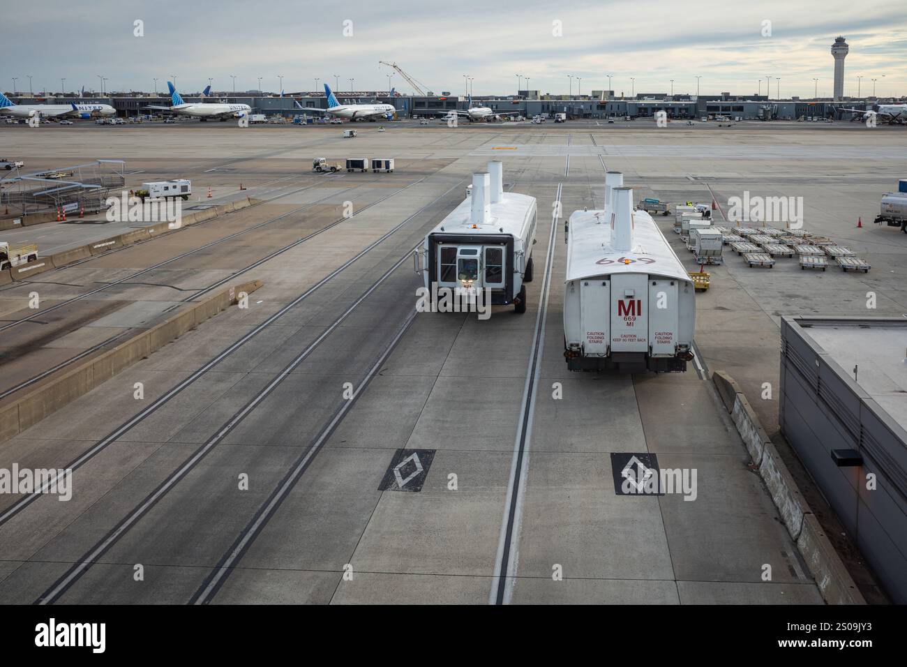 Eine geschäftige Szene am Flughafen Dulles, Washington, mit Bussen, die zwischen Terminals verkehren, eingerahmt vom Kontrollturm und geerdeten Flugzeugen. Stockfoto