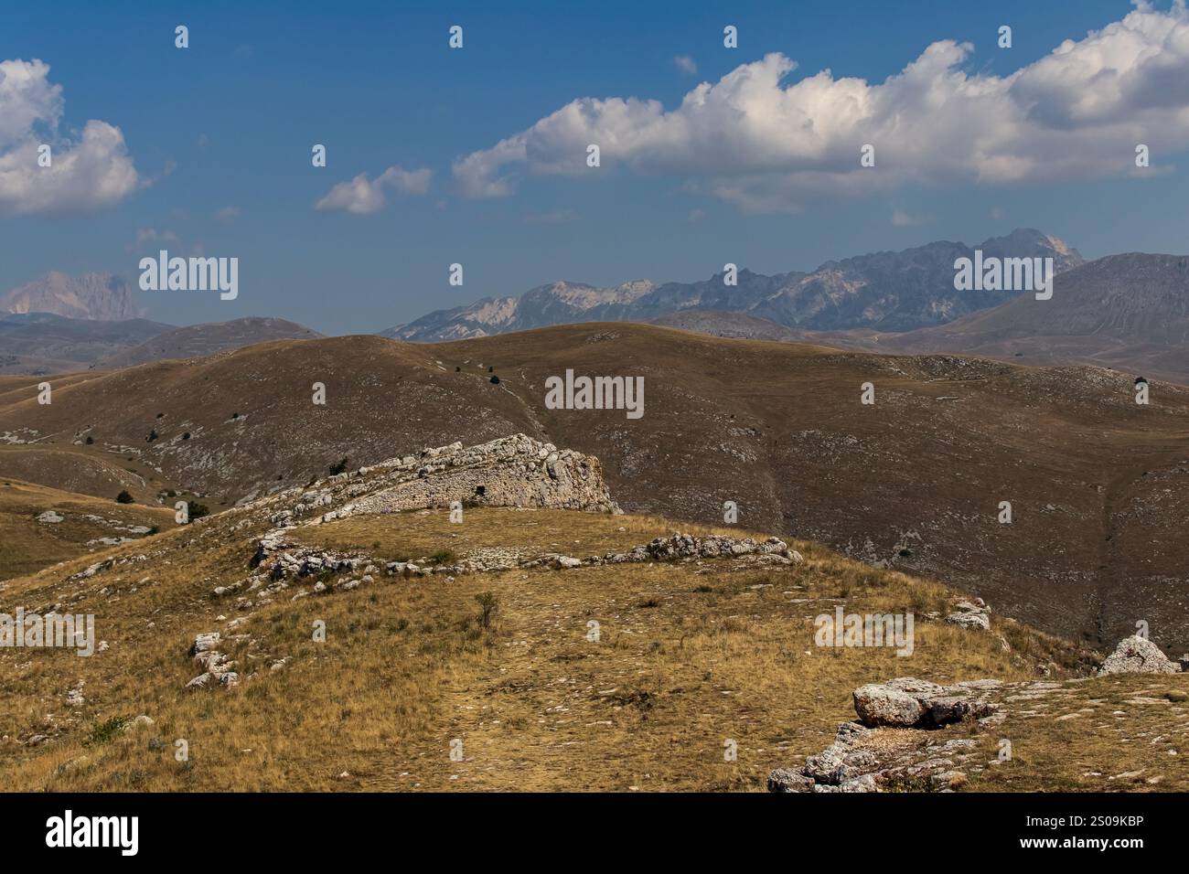 Farbenfrohe Landschaft mit sanften Hügeln unter einem pulsierenden Himmel, mit fernen Bergen, die eine ruhige und majestätische Naturlandschaft schaffen Stockfoto