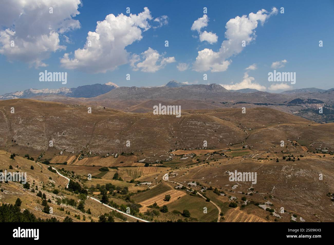 Farbenfrohe Landschaft mit sanften Hügeln unter einem pulsierenden Himmel, mit fernen Bergen, die eine ruhige und majestätische Naturlandschaft schaffen Stockfoto