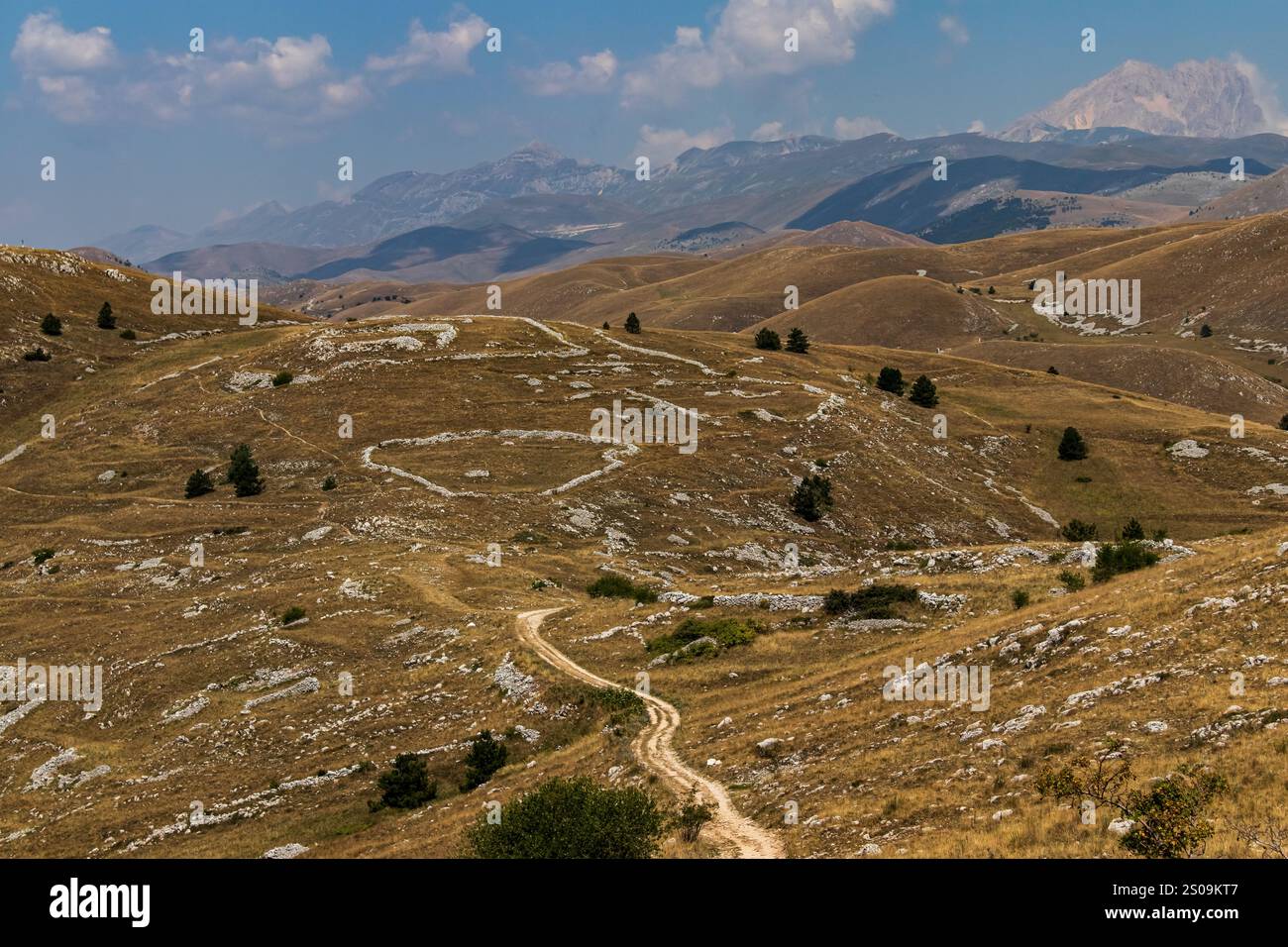 Farbenfrohe Landschaft mit sanften Hügeln unter einem pulsierenden Himmel, mit fernen Bergen, die eine ruhige und majestätische Naturlandschaft schaffen Stockfoto