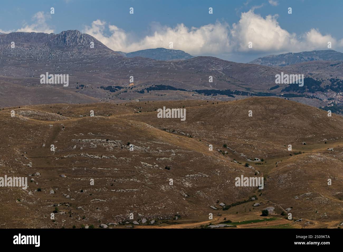 Farbenfrohe Landschaft mit sanften Hügeln unter einem pulsierenden Himmel, mit fernen Bergen, die eine ruhige und majestätische Naturlandschaft schaffen Stockfoto
