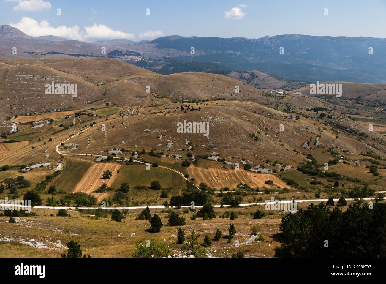 Farbenfrohe Landschaft mit sanften Hügeln unter einem pulsierenden Himmel, mit fernen Bergen, die eine ruhige und majestätische Naturlandschaft schaffen Stockfoto