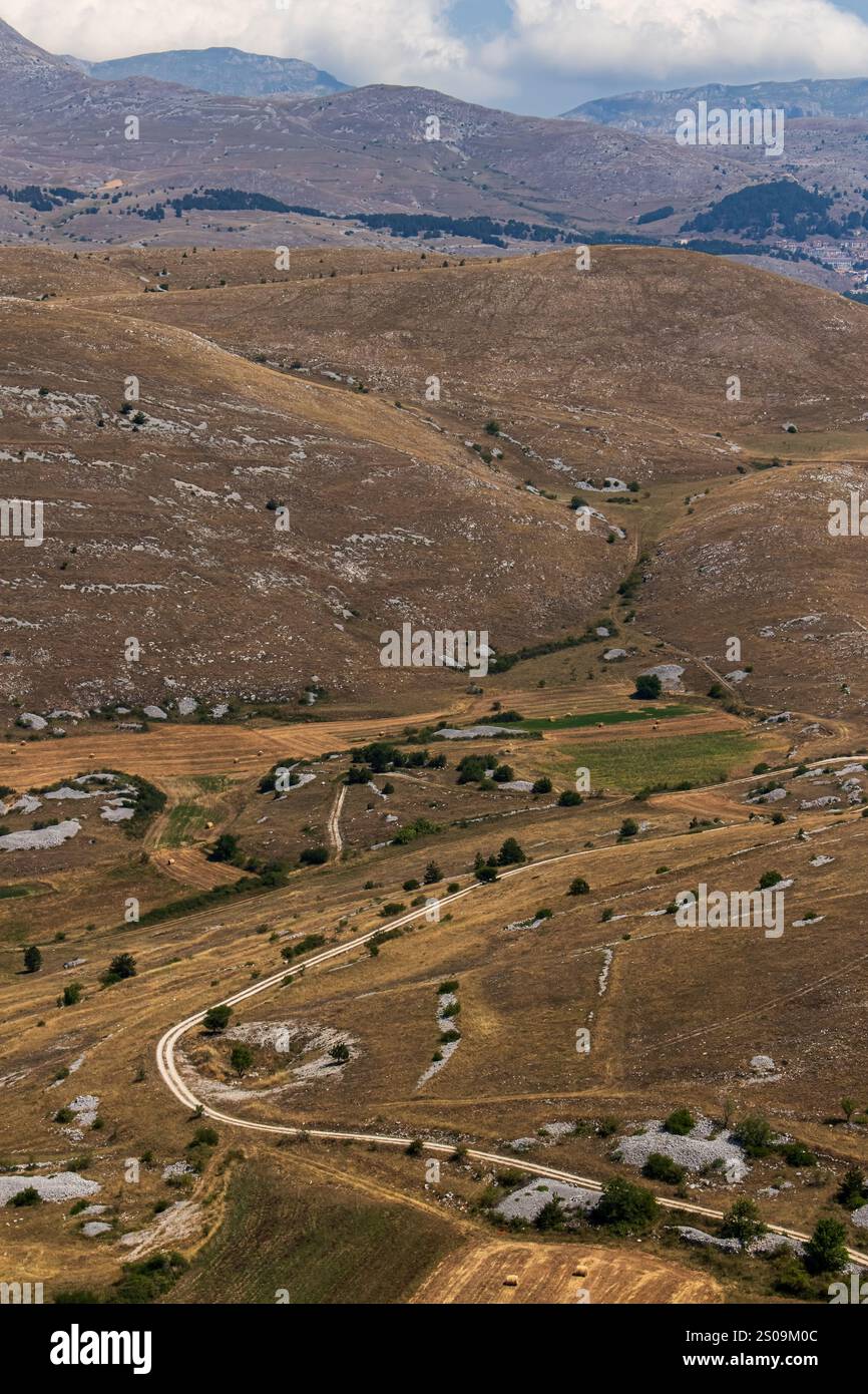 Farbenfrohe Landschaft mit sanften Hügeln unter einem pulsierenden Himmel, mit fernen Bergen, die eine ruhige und majestätische Naturlandschaft schaffen Stockfoto