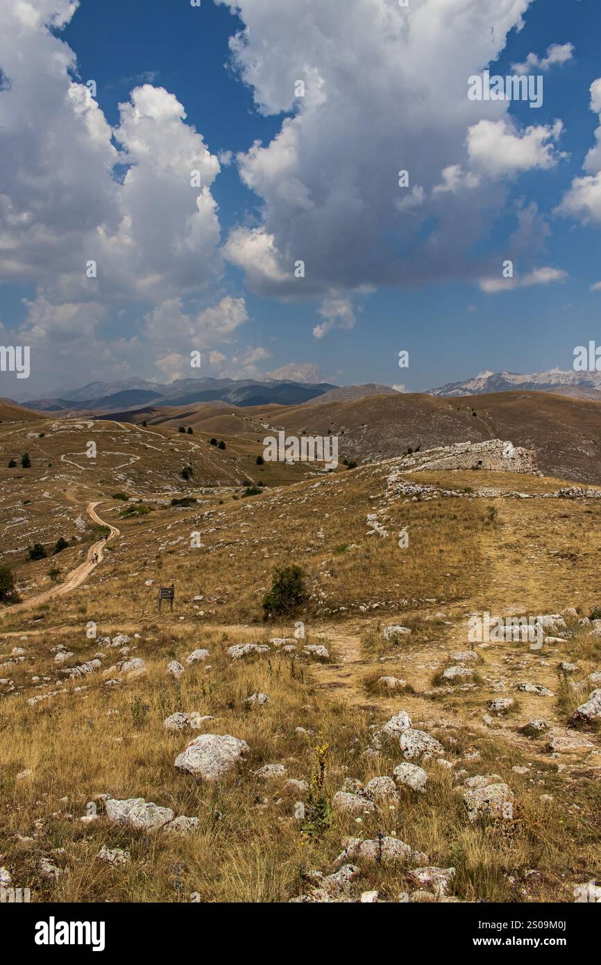 Farbenfrohe Landschaft mit sanften Hügeln unter einem pulsierenden Himmel, mit fernen Bergen, die eine ruhige und majestätische Naturlandschaft schaffen Stockfoto