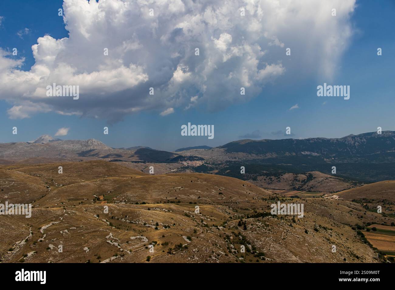 Farbenfrohe Landschaft mit sanften Hügeln unter einem pulsierenden Himmel, mit fernen Bergen, die eine ruhige und majestätische Naturlandschaft schaffen Stockfoto