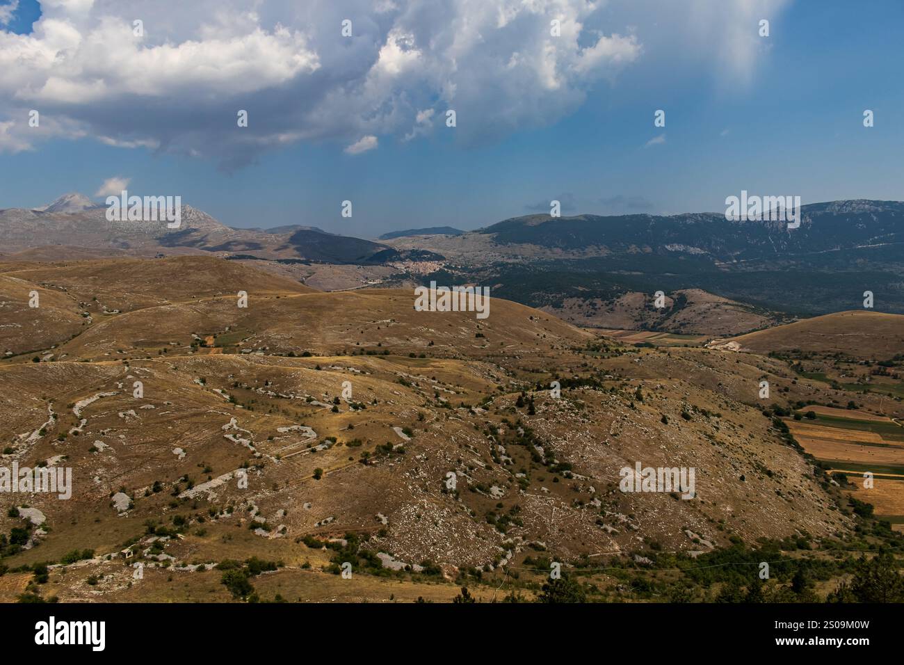 Farbenfrohe Landschaft mit sanften Hügeln unter einem pulsierenden Himmel, mit fernen Bergen, die eine ruhige und majestätische Naturlandschaft schaffen Stockfoto