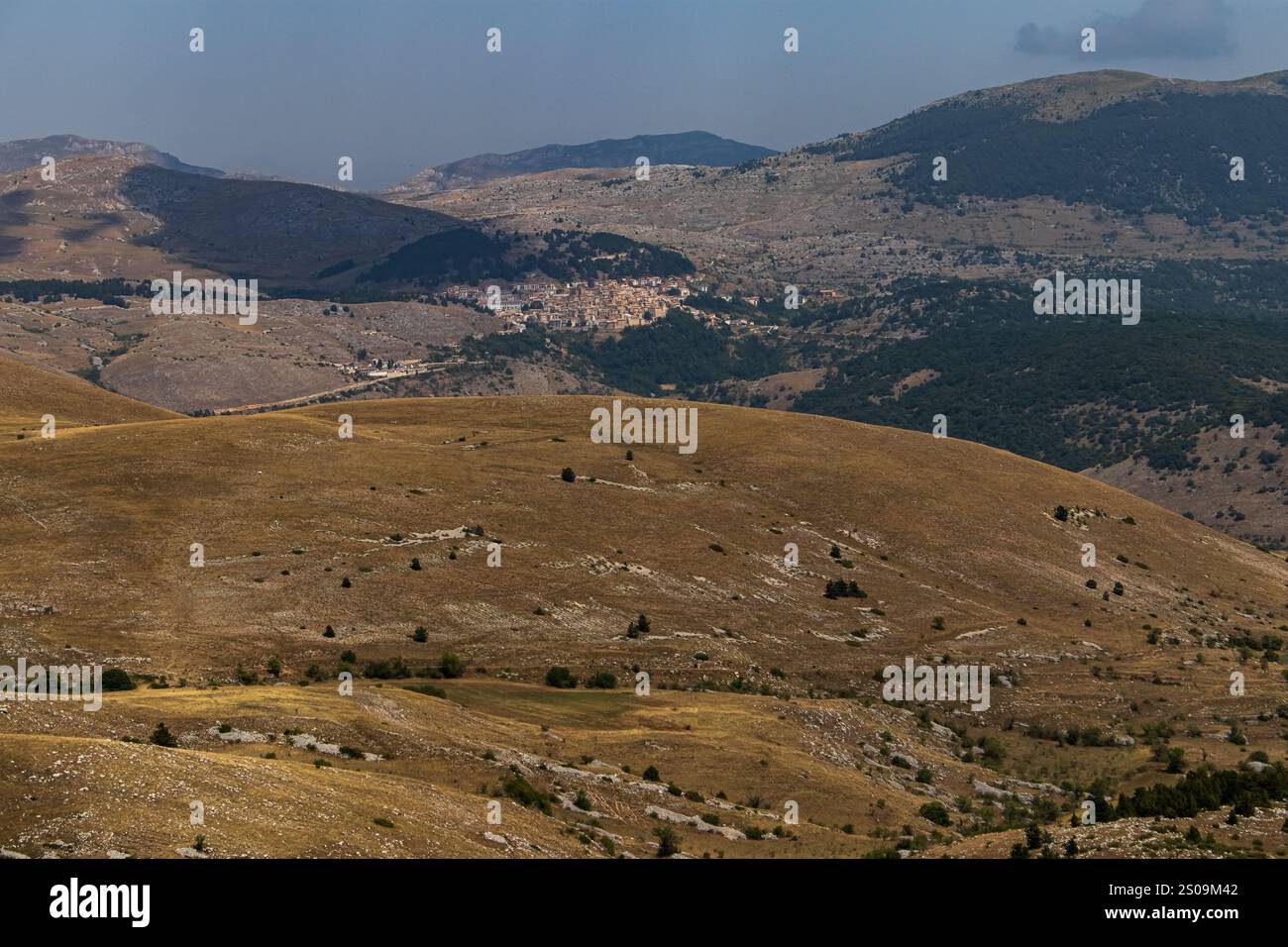 Farbenfrohe Landschaft mit sanften Hügeln unter einem pulsierenden Himmel, mit fernen Bergen, die eine ruhige und majestätische Naturlandschaft schaffen Stockfoto