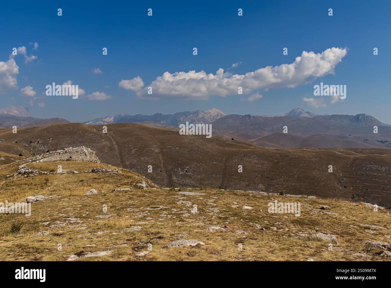 Farbenfrohe Landschaft mit sanften Hügeln unter einem pulsierenden Himmel, mit fernen Bergen, die eine ruhige und majestätische Naturlandschaft schaffen Stockfoto