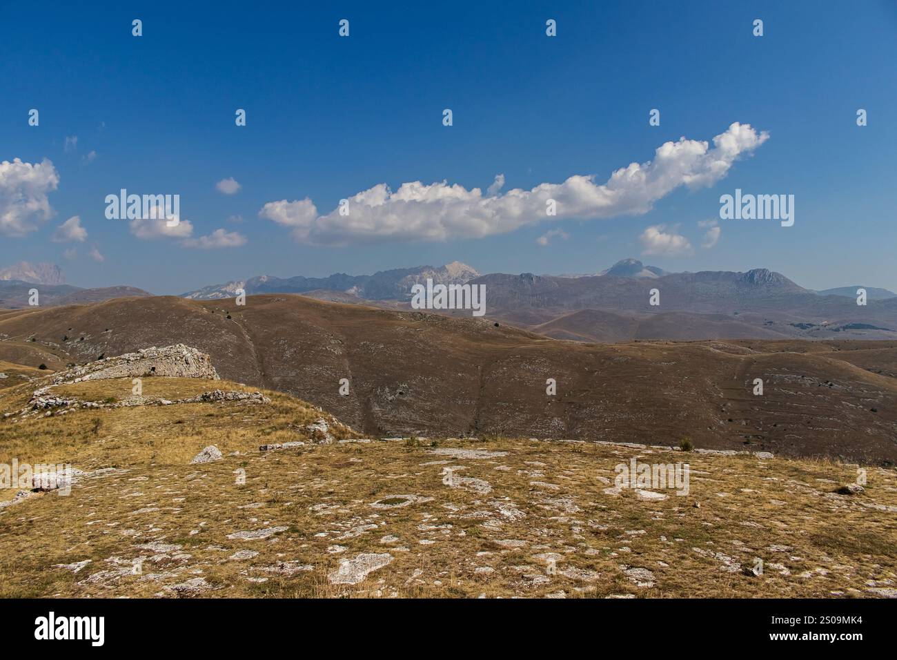 Farbenfrohe Landschaft mit sanften Hügeln unter einem pulsierenden Himmel, mit fernen Bergen, die eine ruhige und majestätische Naturlandschaft schaffen Stockfoto