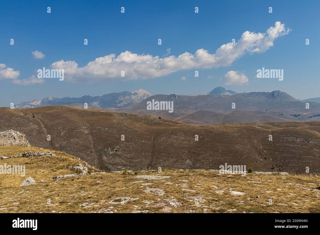 Farbenfrohe Landschaft mit sanften Hügeln unter einem pulsierenden Himmel, mit fernen Bergen, die eine ruhige und majestätische Naturlandschaft schaffen Stockfoto