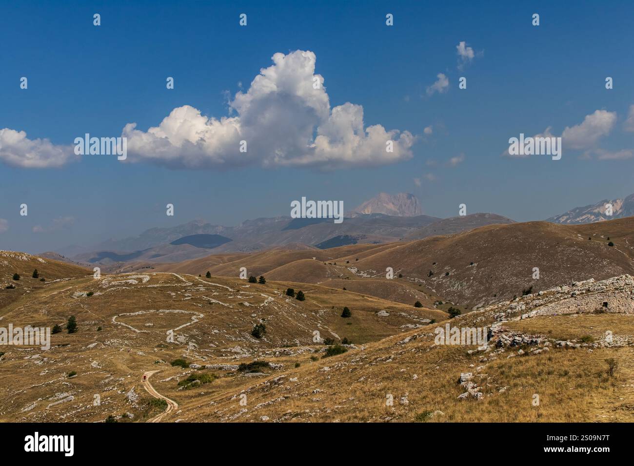 Farbenfrohe Landschaft mit sanften Hügeln unter einem pulsierenden Himmel, mit fernen Bergen, die eine ruhige und majestätische Naturlandschaft schaffen Stockfoto