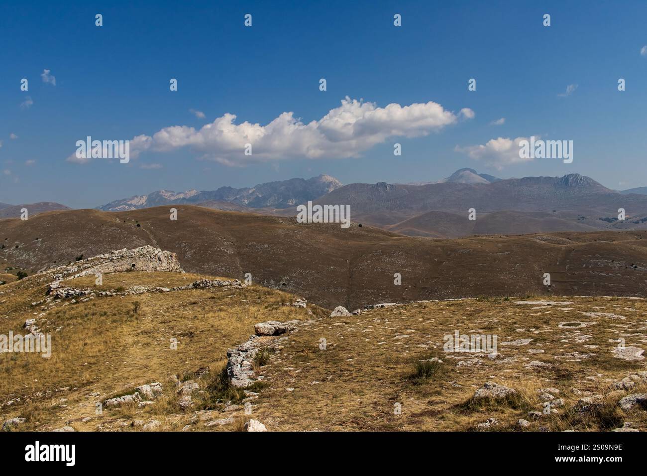 Farbenfrohe Landschaft mit sanften Hügeln unter einem pulsierenden Himmel, mit fernen Bergen, die eine ruhige und majestätische Naturlandschaft schaffen Stockfoto