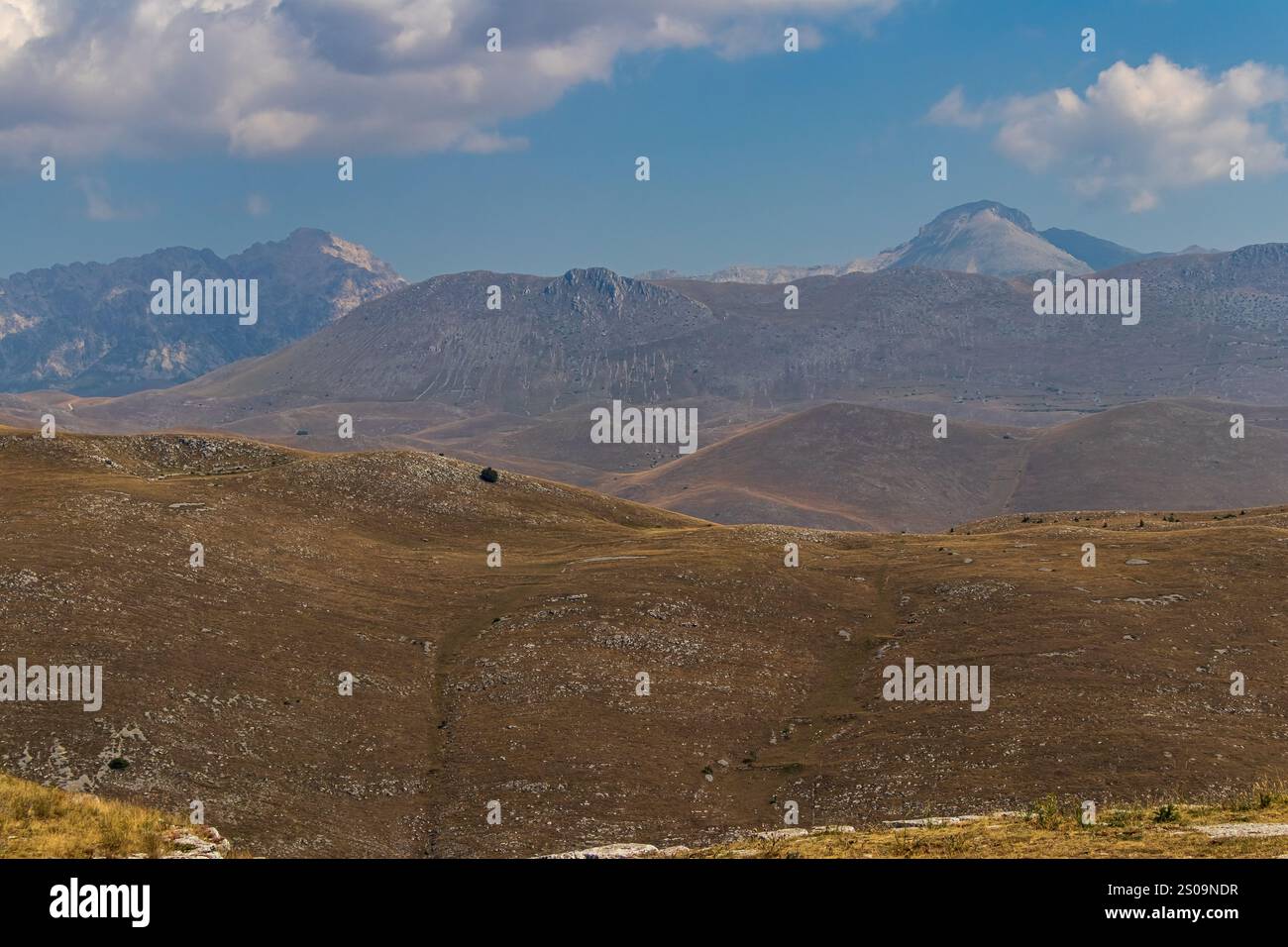 Farbenfrohe Landschaft mit sanften Hügeln unter einem pulsierenden Himmel, mit fernen Bergen, die eine ruhige und majestätische Naturlandschaft schaffen Stockfoto