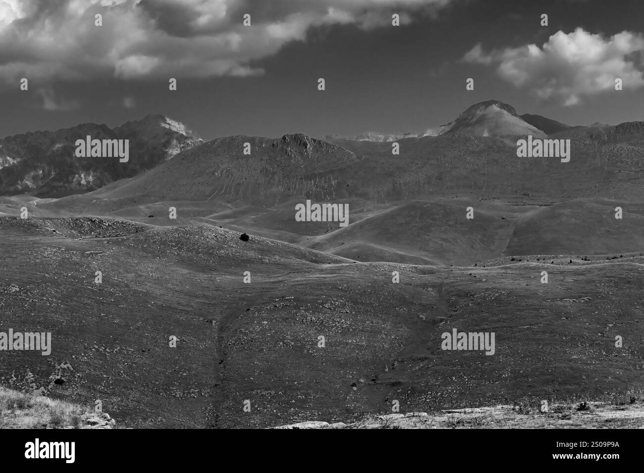 Schwarz-weiße Landschaft mit dramatischem Himmel und kargen Hügeln, die die zeitlose Schönheit und das Wesen der Natur einfangen Stockfoto