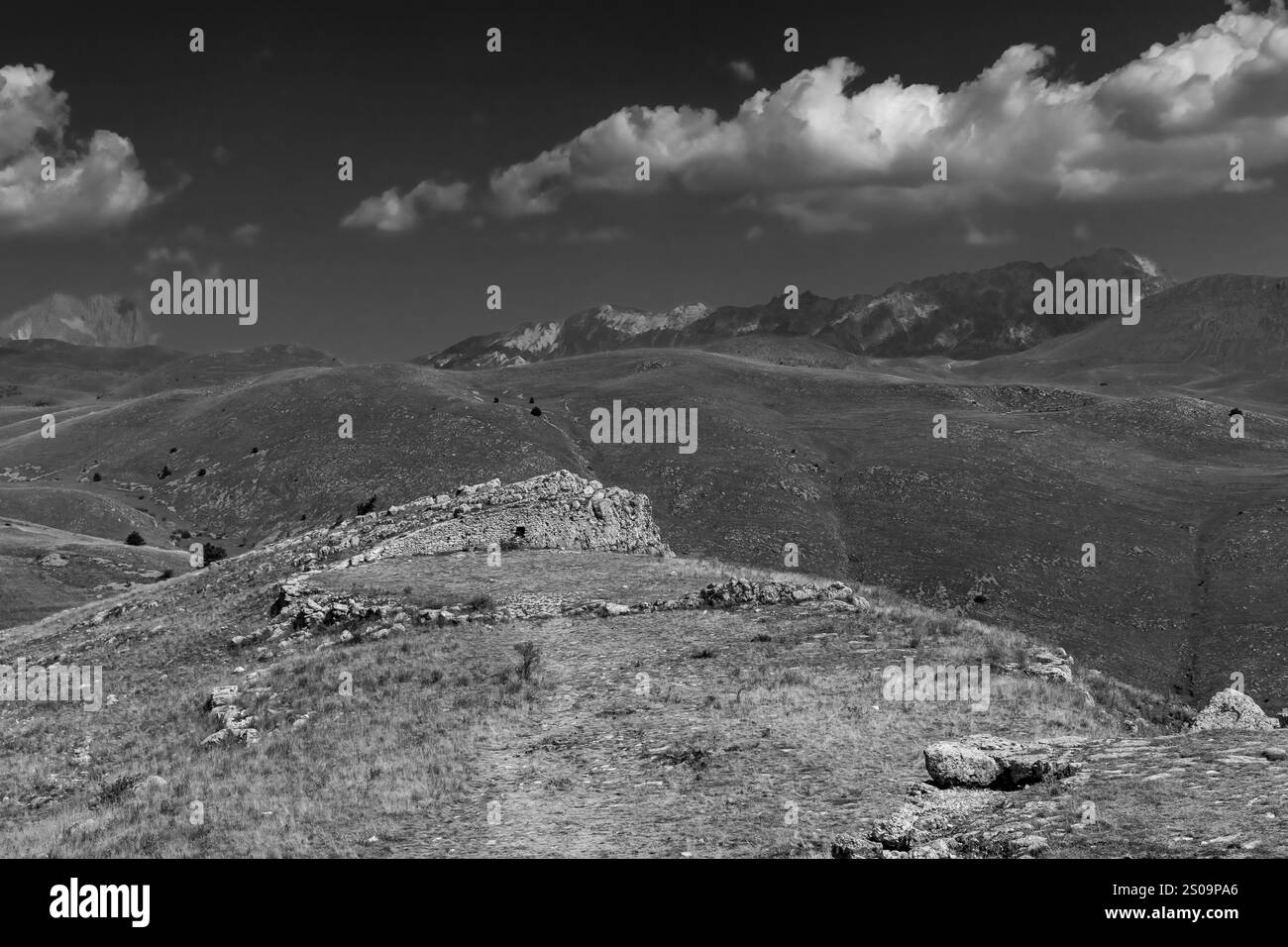 Schwarz-weiße Landschaft mit dramatischem Himmel und kargen Hügeln, die die zeitlose Schönheit und das Wesen der Natur einfangen Stockfoto