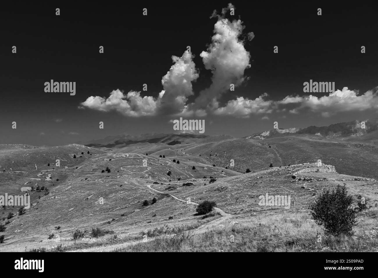 Schwarz-weiße Landschaft mit dramatischem Himmel und kargen Hügeln, die die zeitlose Schönheit und das Wesen der Natur einfangen Stockfoto