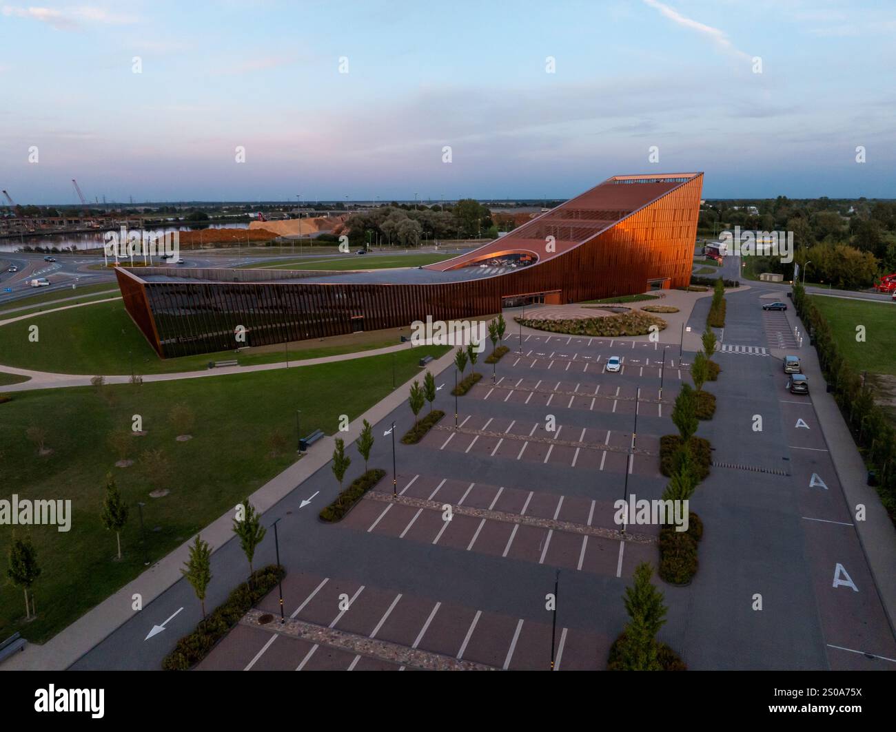 Das Wissenschafts- und Innovationszentrum Ventspils in Lettland verfügt über ein modernes, eckiges Design mit einer rostfarbenen Fassade, umgeben von gut gepflegtem Erdreich Stockfoto