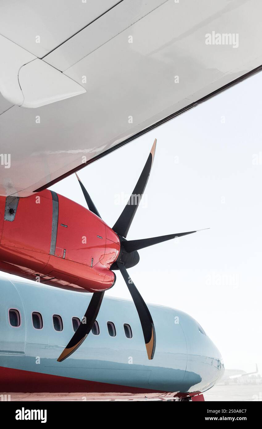 Blick unter einem Flügel eines blauen Turboprop-Flugzeugs mit roten Streifen und Motorverkleidungen. Passagierflugzeug mit Propellermotor. Stockfoto