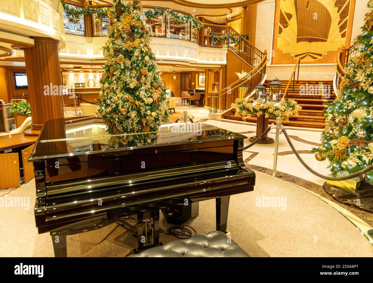 Kreuzfahrtschiff Cunard Queen Elizabeth, Innenraum des Kreuzfahrtschiffes mit Weihnachtsdekorationen und weihnachtsbäumen um das Klavier in der Großen Treppe Stockfoto