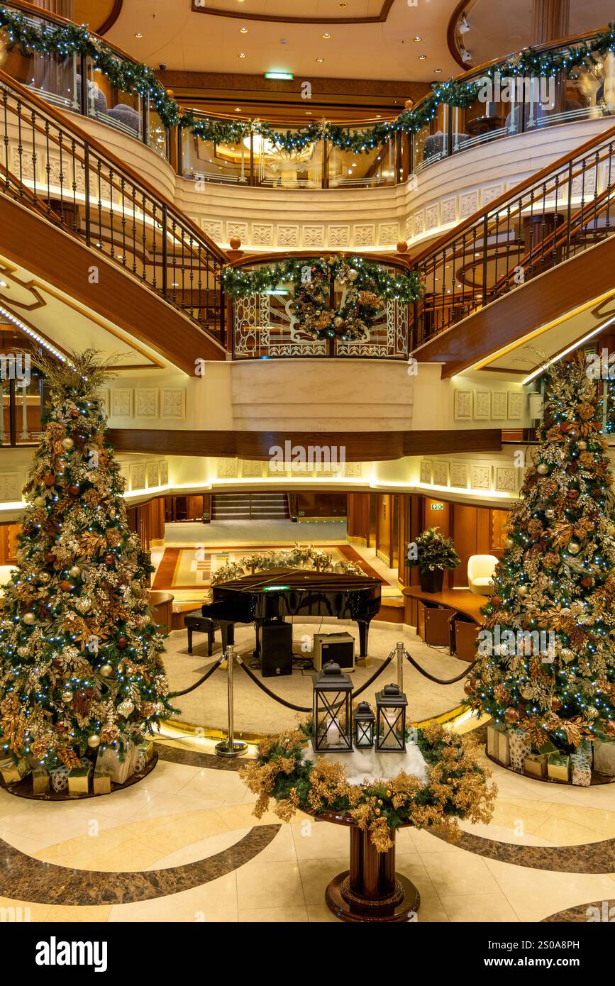 Kreuzfahrtschiff Cunard Queen Elizabeth, Innenraum des Kreuzfahrtschiffes mit Weihnachtsdekorationen und weihnachtsbäumen um das Klavier in der Großen Treppe Stockfoto