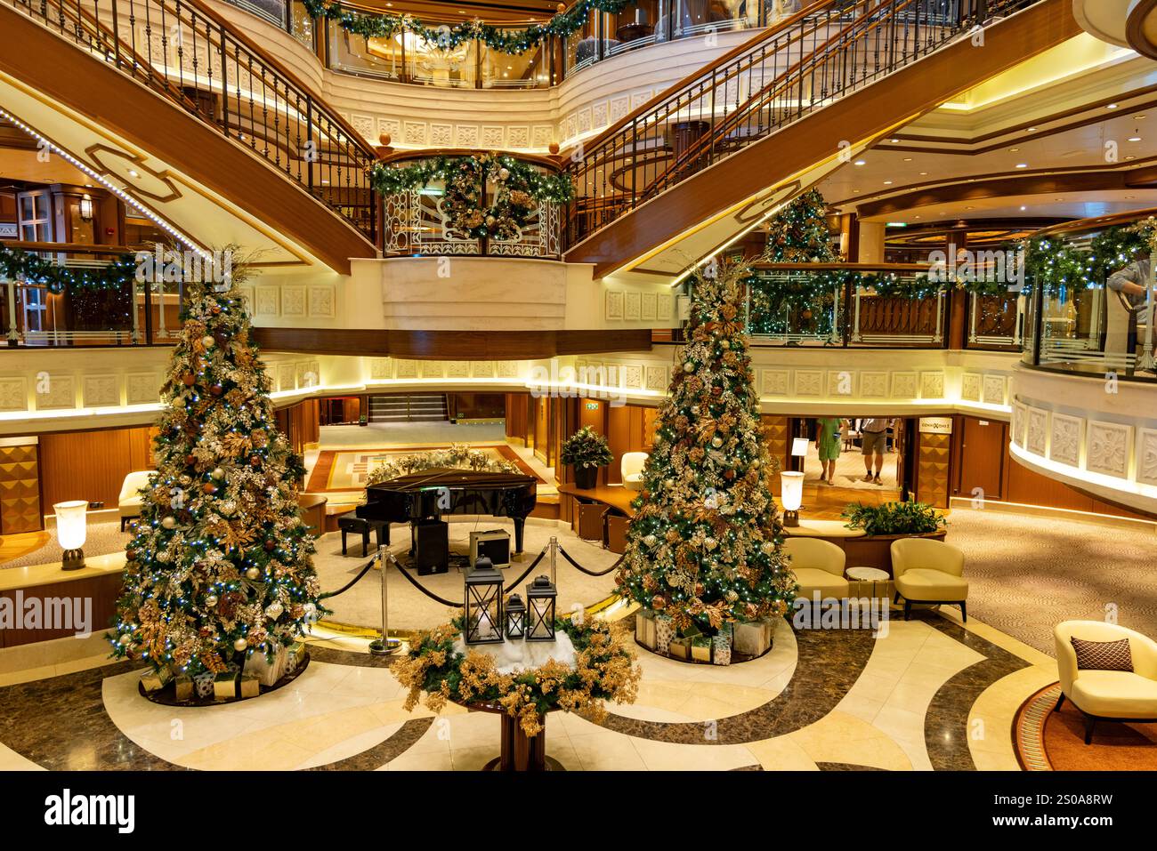 Kreuzfahrtschiff Cunard Queen Elizabeth, Innenraum des Kreuzfahrtschiffes mit Weihnachtsdekorationen und weihnachtsbäumen um das Klavier in der Großen Treppe Stockfoto