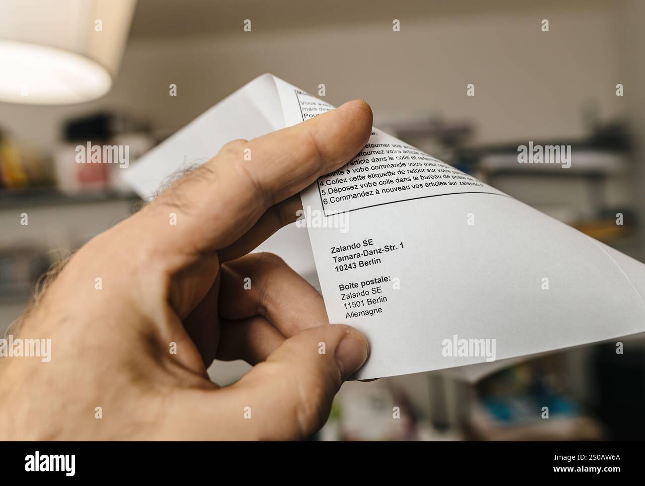 Paris, Frankreich – 25. Oktober 2023: Hand in der Hand eines Rücksendedokuments von Zalando SE mit Anweisungen und einer Rücksendeadresse in Berlin, Deutschland, zur Bearbeitung von Kundenrücksendungen Stockfoto