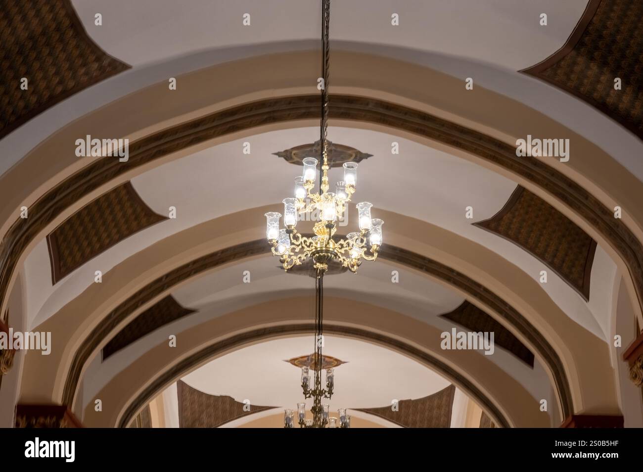 Elegante architektonische Details und ein atemberaubender Kronleuchter beleuchten einen großen Flur. Klassisches Design vom Feinsten. Stockfoto