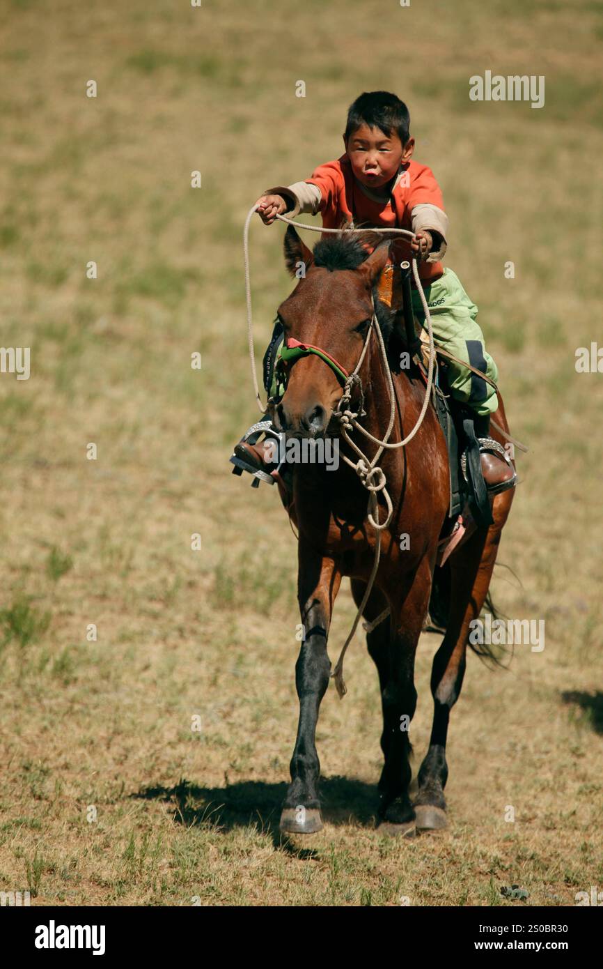 Eine Gruppe mongolischer Kinder, die auf Pferden ein Naadam-Rennen zu Ehren einer Gruppe von Turisten machen, die den Gorkhi-Terelj-Nationalpark besuchen Stockfoto