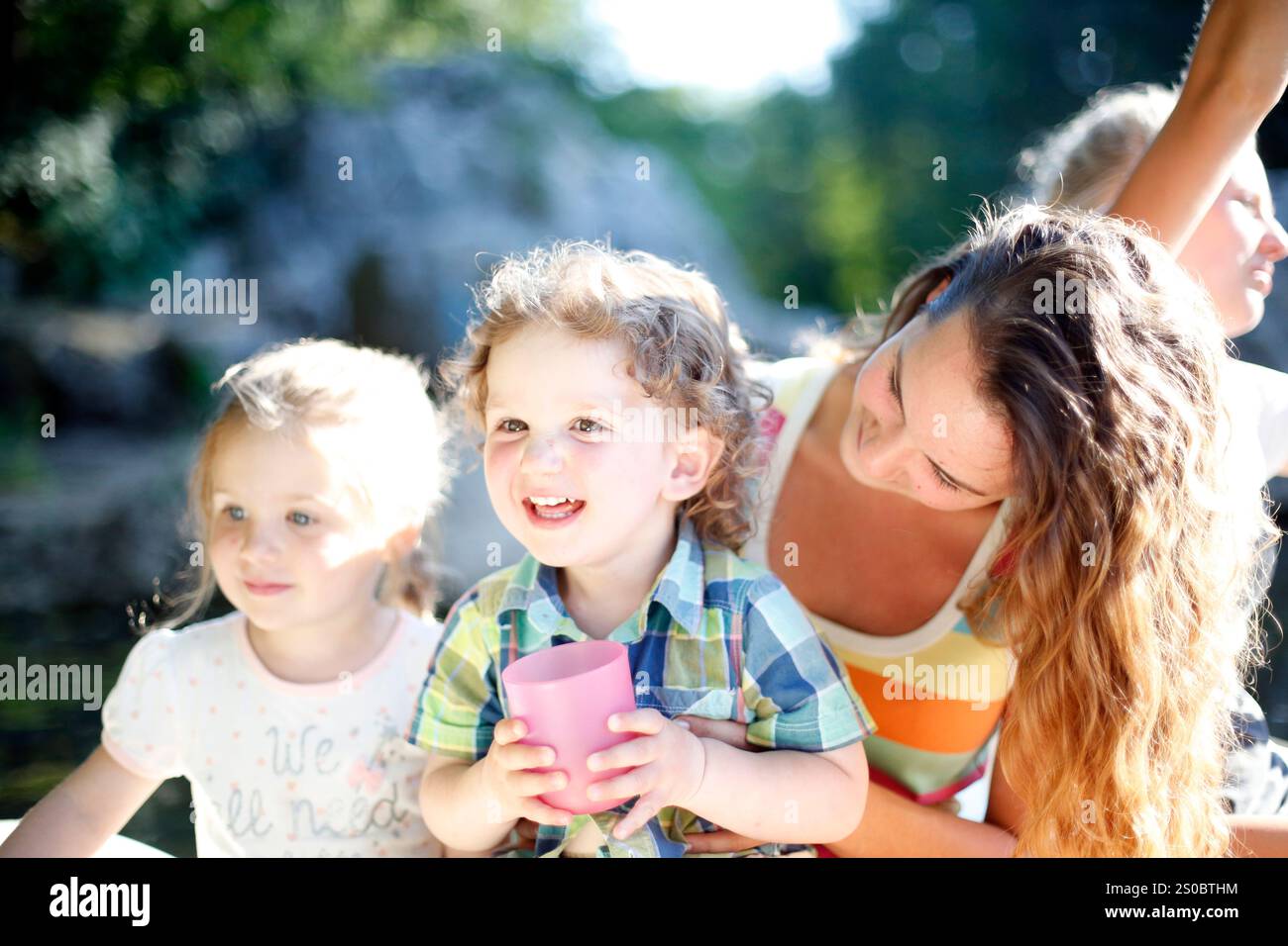 Frau und zwei Kinder sitzen draußen Stockfoto