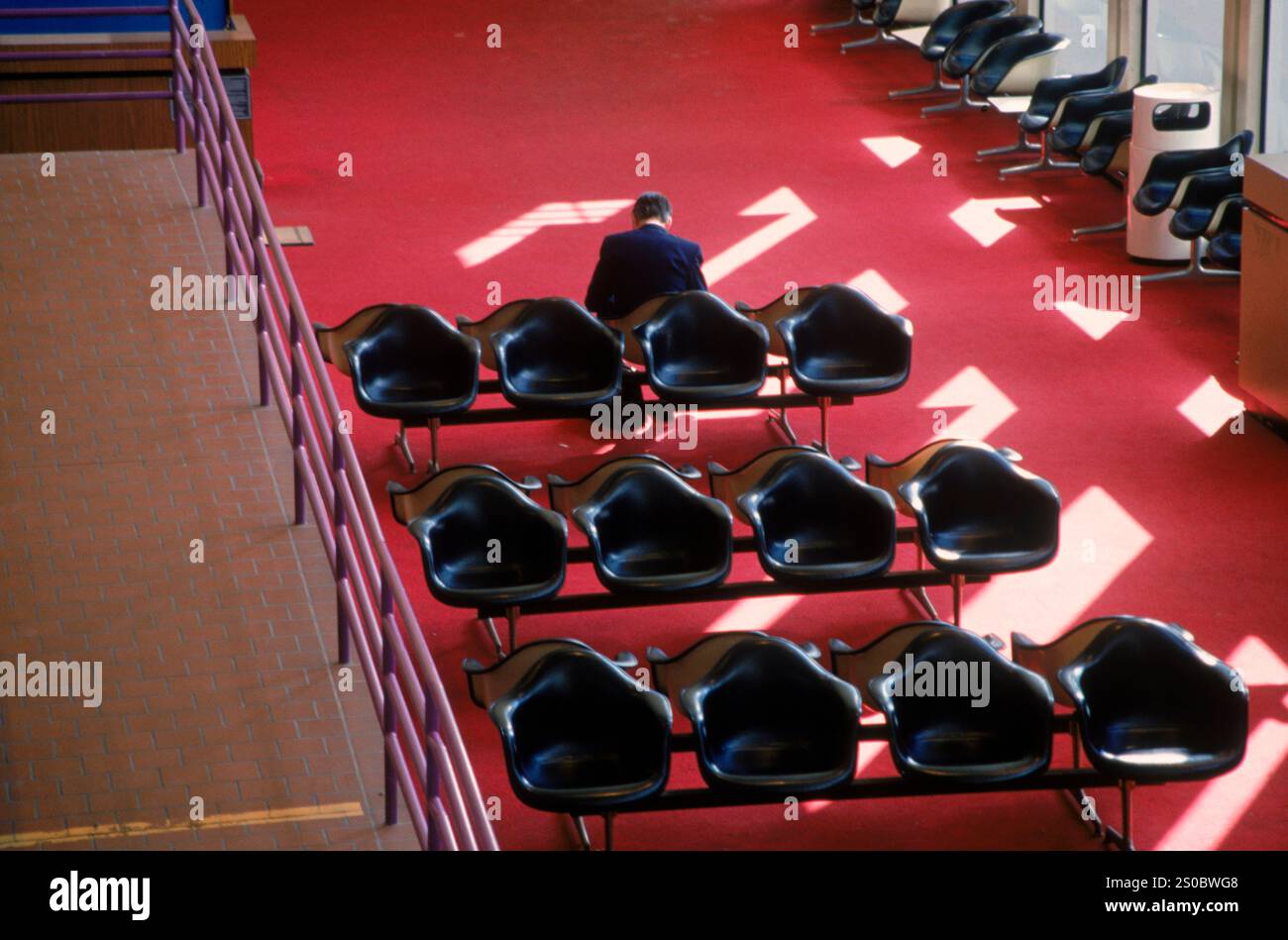 Ein Mann sitzt in der Lobby eines Flughafens. Stockfoto