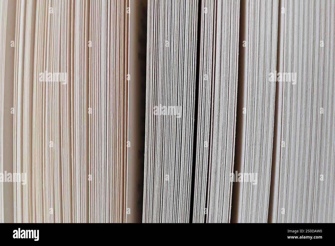 Nahaufnahme der Seiten eines Hardcover-Buches, die den dichten Stapel von Seiten mit sichtbaren Lücken zwischen ihnen zeigt. Durch die mehrschichtige Textur der Seiten wird ein erzeugt Stockfoto