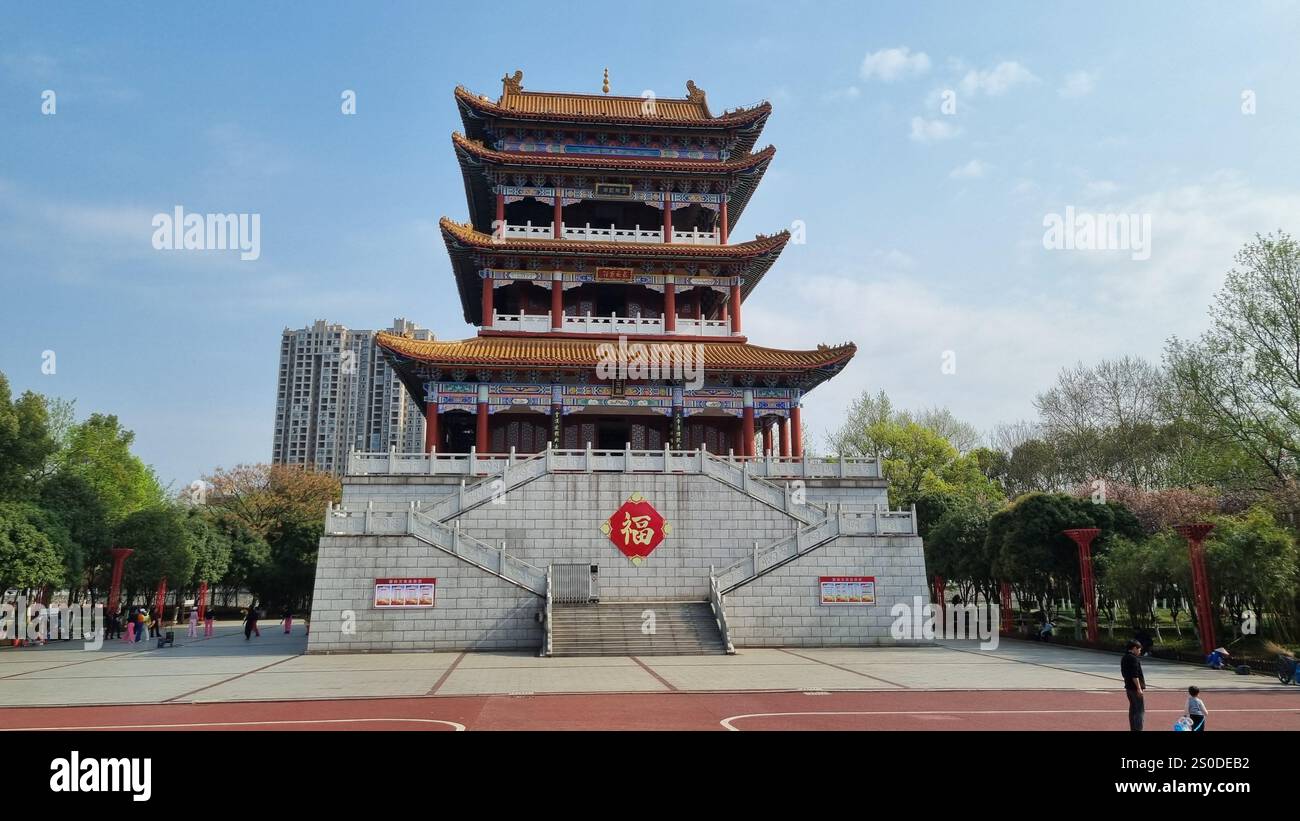 Ein traditioneller Pavillon oder eine Pagode im chinesischen Stil mit leuchtenden roten, blauen und gelben Akzenten. - Smartphone-aufgenommenes Stockfoto