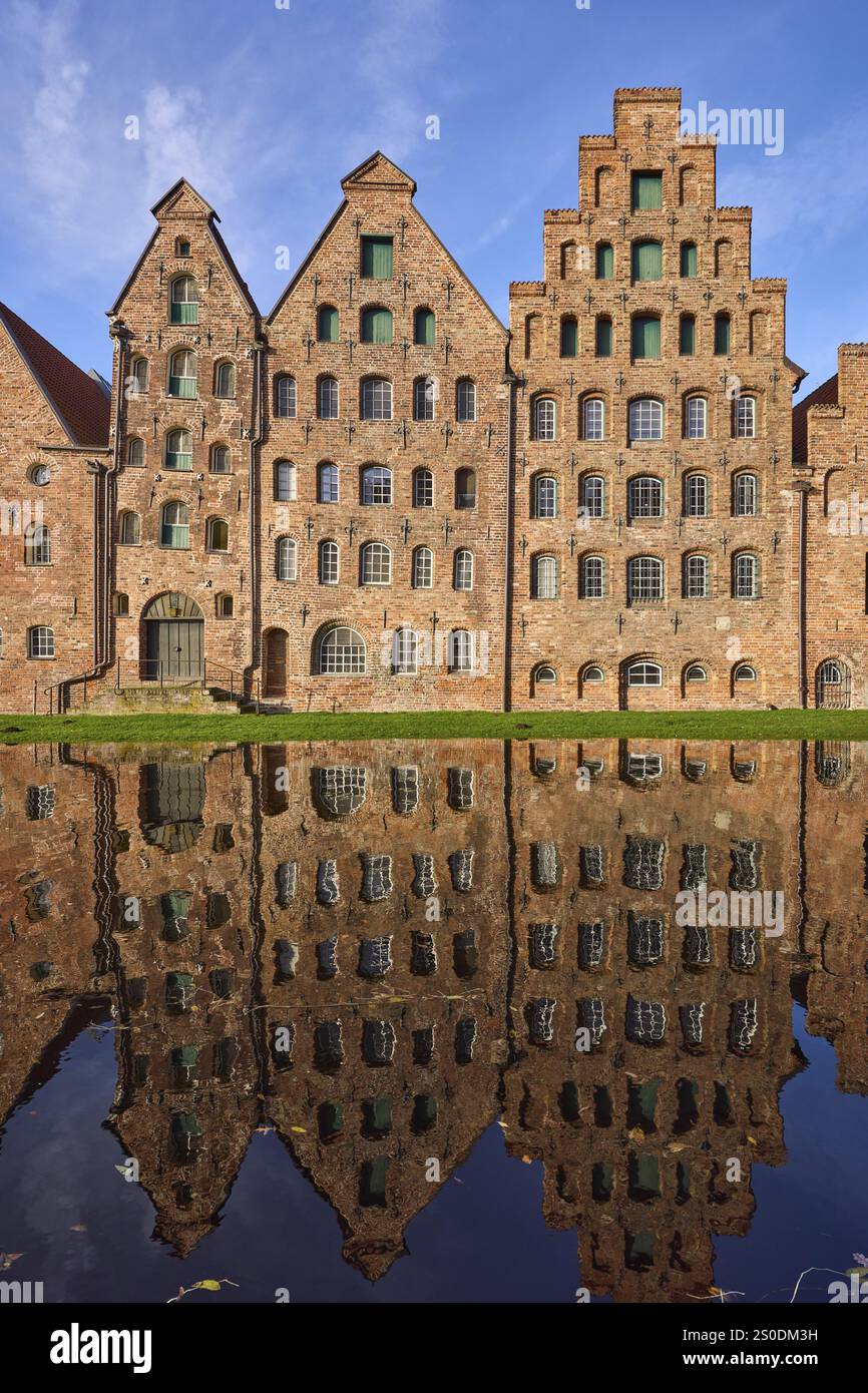 Historische Salzlager, Backsteinbauten, die sich auf der Wasseroberfläche der Trave spiegeln, blauer Himmel mit Schleierwolken, Hansestadt Lübeck, independe Stockfoto