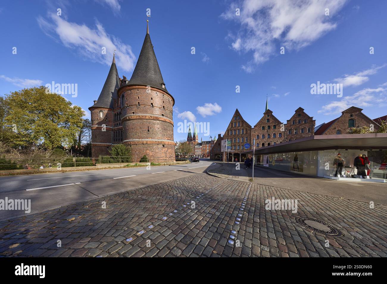 Lübeck Holstentor, Seitenansicht, Fußgängerübergang, Kopfsteinpflaster, blauer Himmel mit Schönwetterwolken, Kreuzung Wallstraße mit Holstentorp Stockfoto