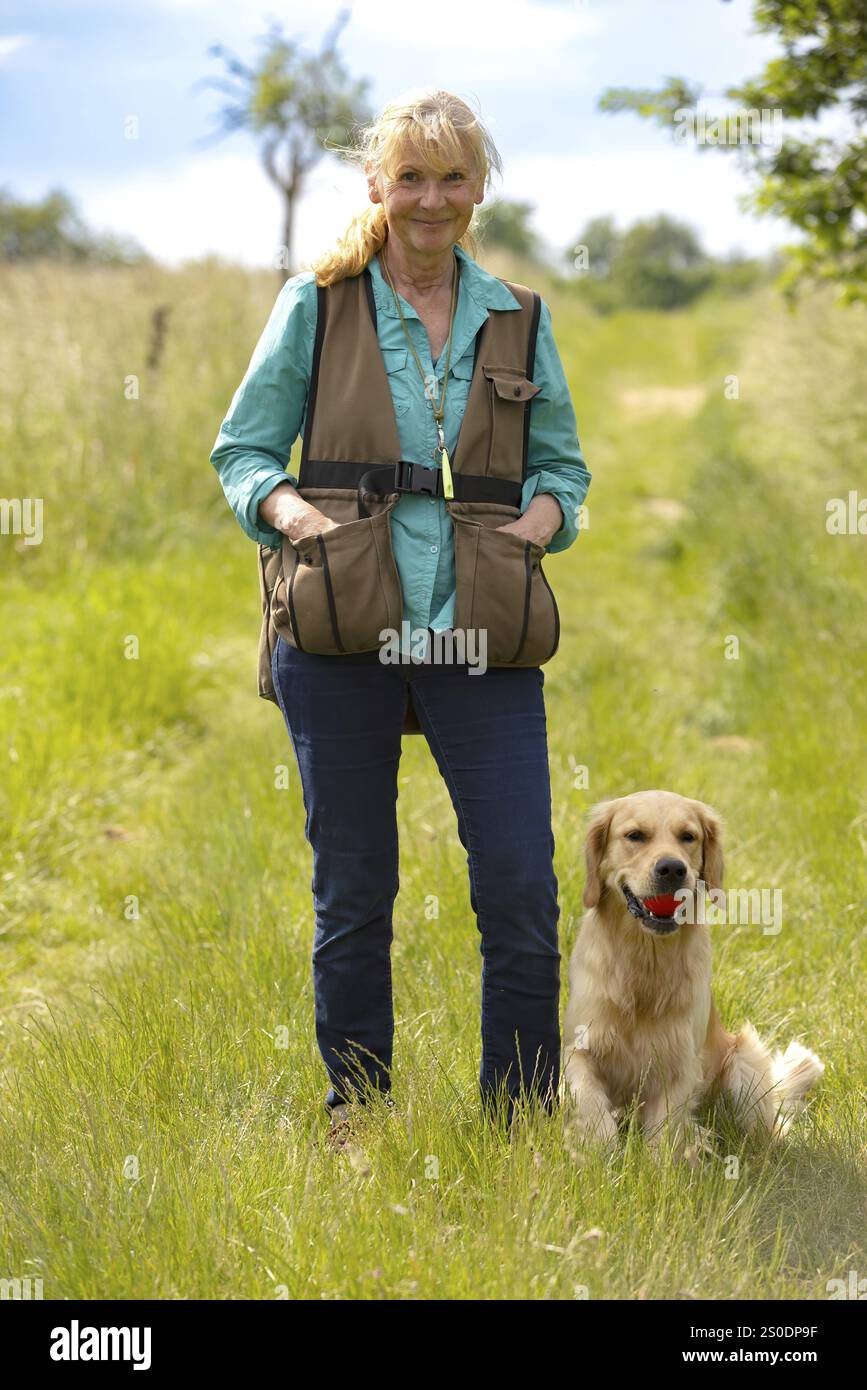 Eine Frau mit einer Dummy-Weste und ihrem gehorsamen goldenen Retriever Stockfoto