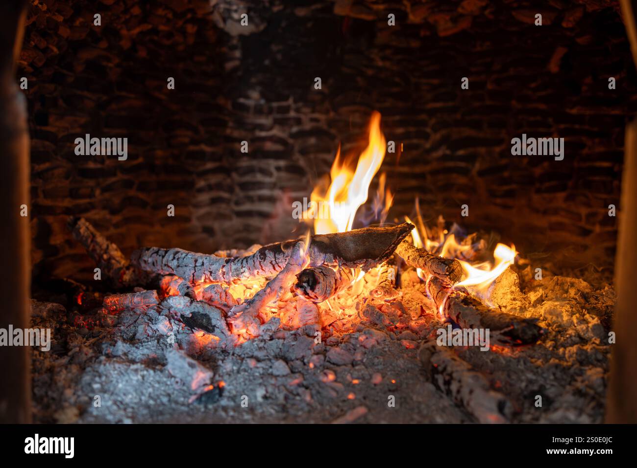 Nahaufnahme von Flammen und glühender Glut in einem rustikalen Holzofen Stockfoto Nahaufnahme von Flammen und glühender Glut in einem rustikalen Holzofen Stockfoto