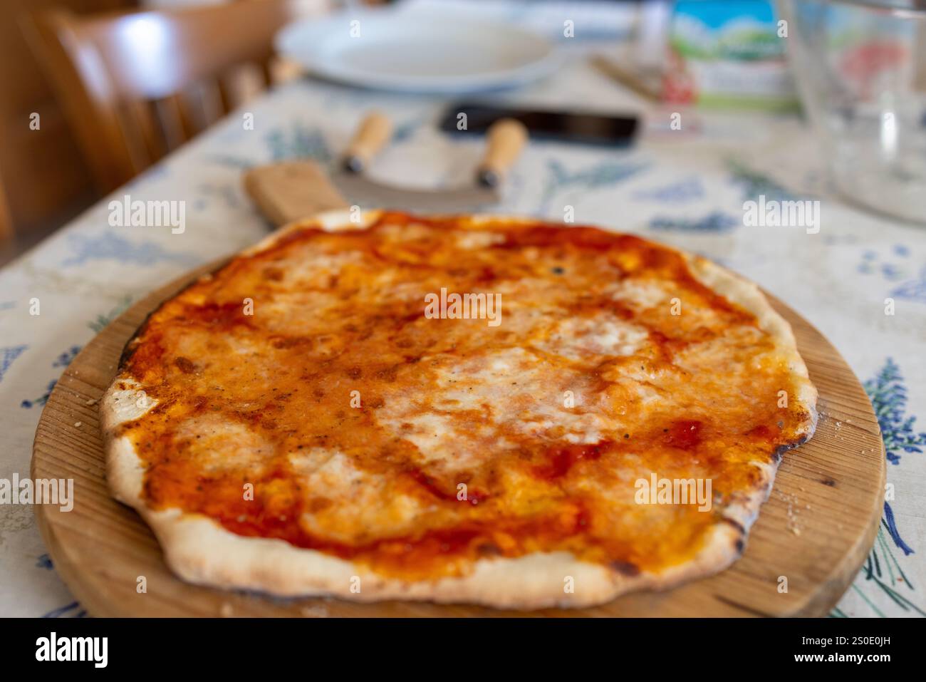 Eine Nahaufnahme einer frisch gebackenen hausgemachten Pizza mit Tomatensauce und geschmolzenem Käse, präsentiert auf einer rustikalen Holzserviertafel. Stockfoto