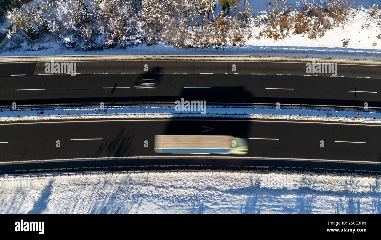 Luftaufnahme eines Lastwagens und Autos auf einem verschneiten Winter Highway Stockfoto