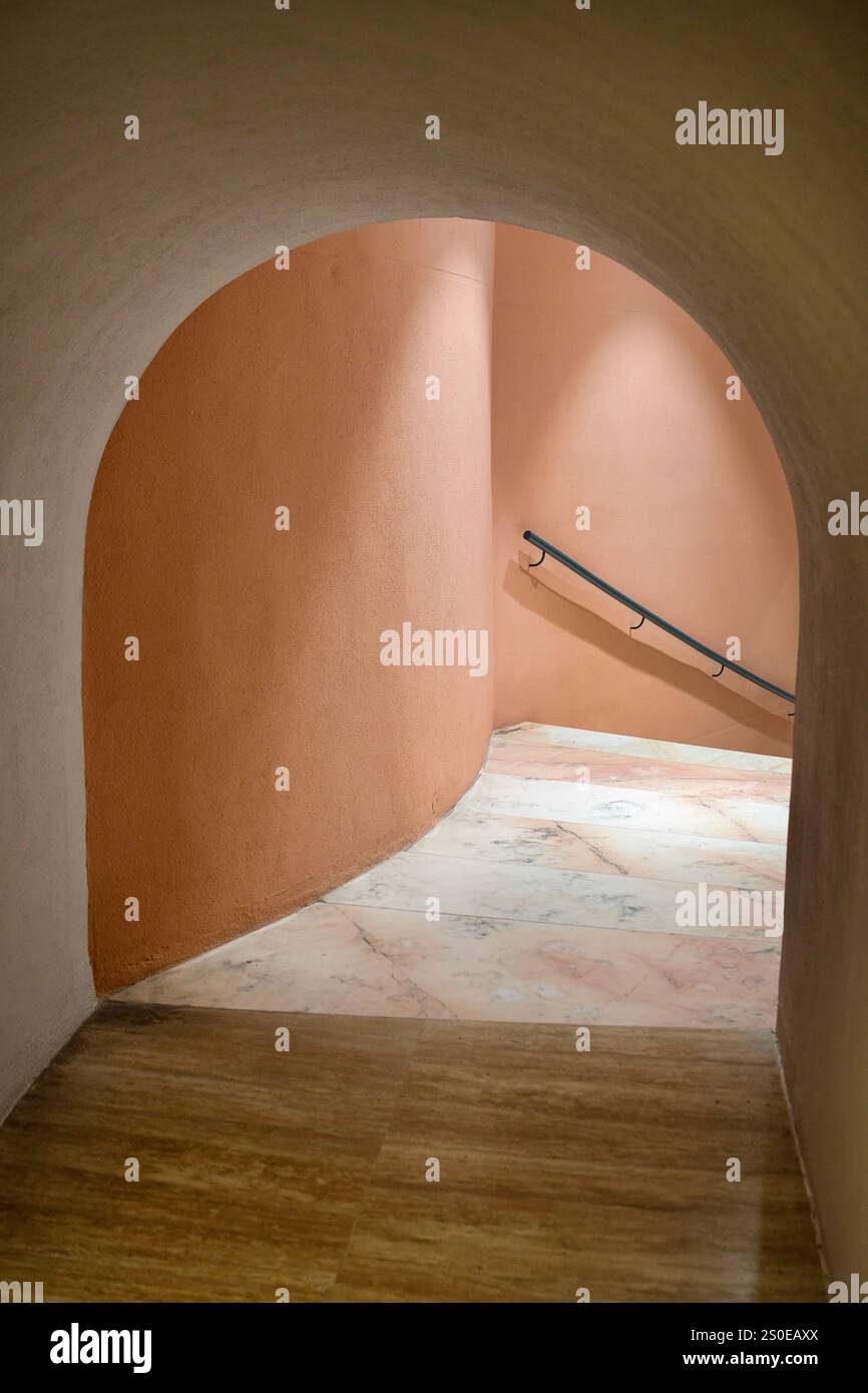 Licht und Schatten oben auf einer Treppe mit einer pinkfarbenen Wand, durch einen Bogengang gesehen. Stockfoto