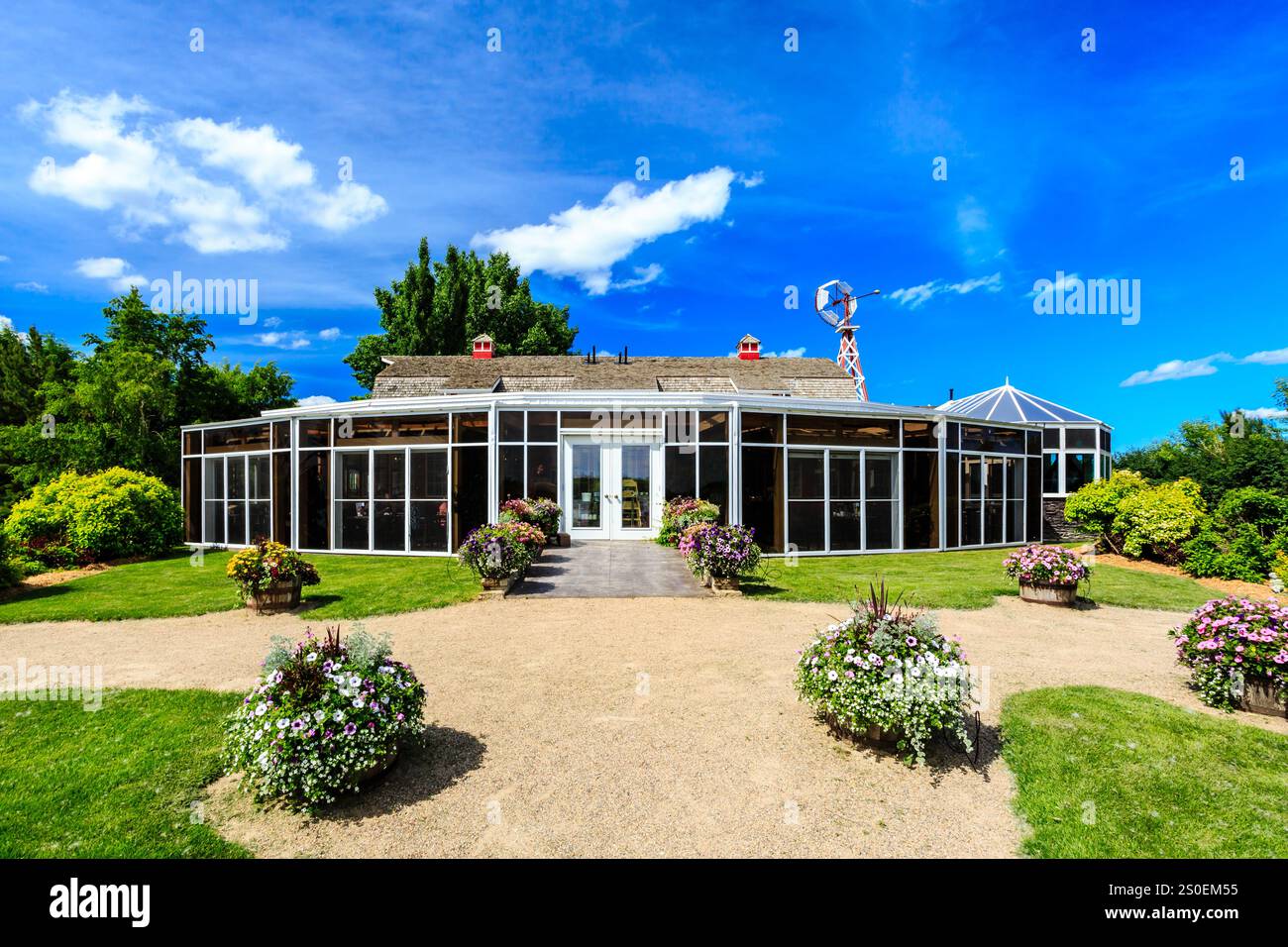 Ein großes Gebäude mit einem grünen Dach und einer weißen Fassade. Das Gebäude hat ein großes Glasfenster und eine große Glastür. Das Gebäude ist umgeben von einem Stockfoto