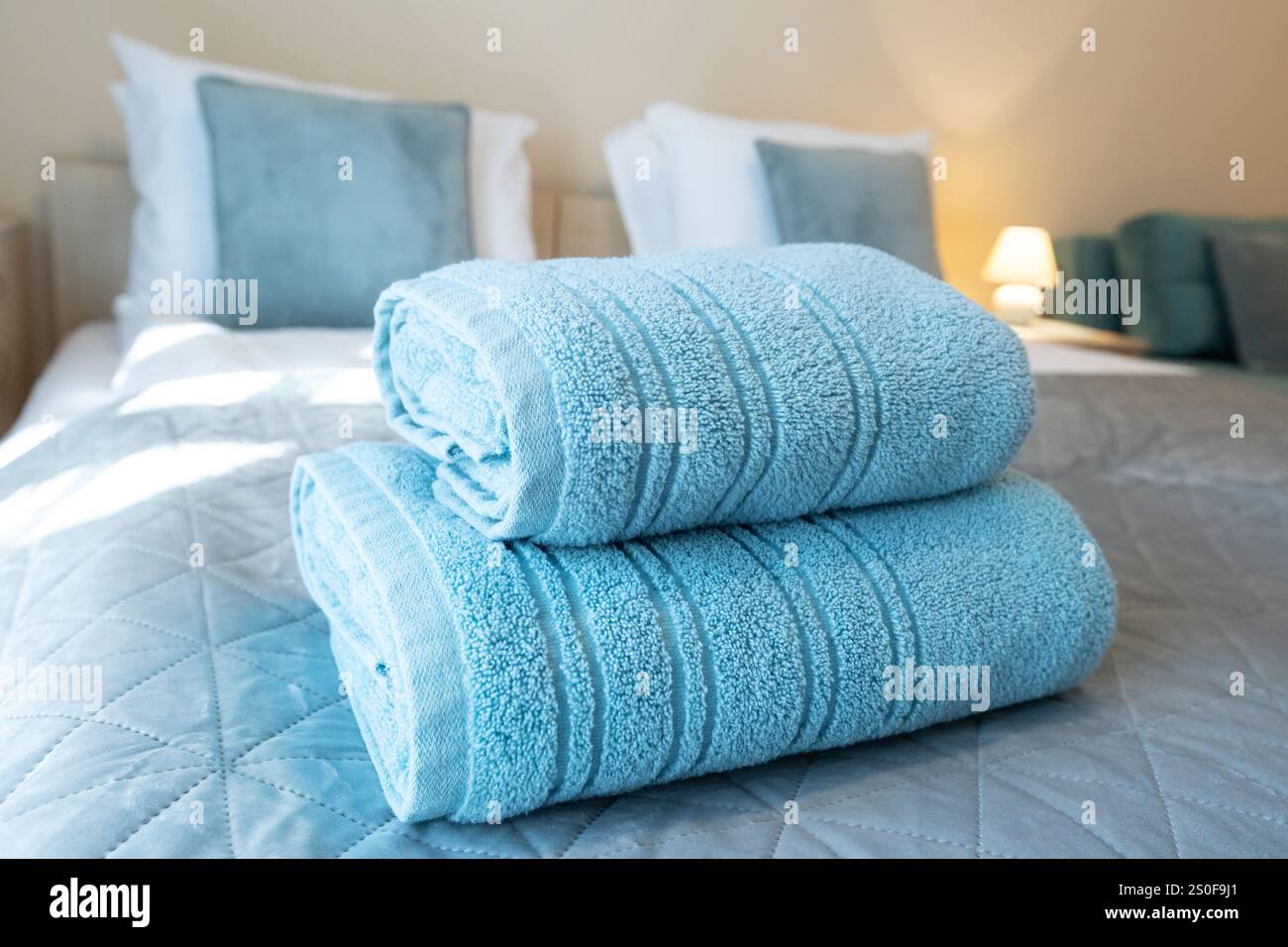Türkisfarbene Handtücher, die für Hotelgäste auf dem Bett gefaltet wurden Stockfoto