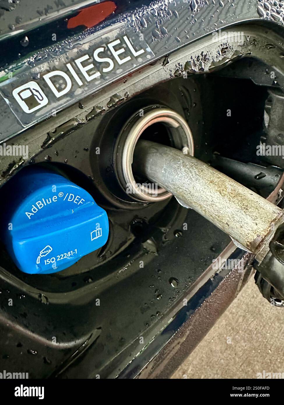 Betanken eines Autos mit Diesel, Nahaufnahme der Feeling Pistole mit einem Schild über dem - Smartphone-aufgenommenes Stockfoto