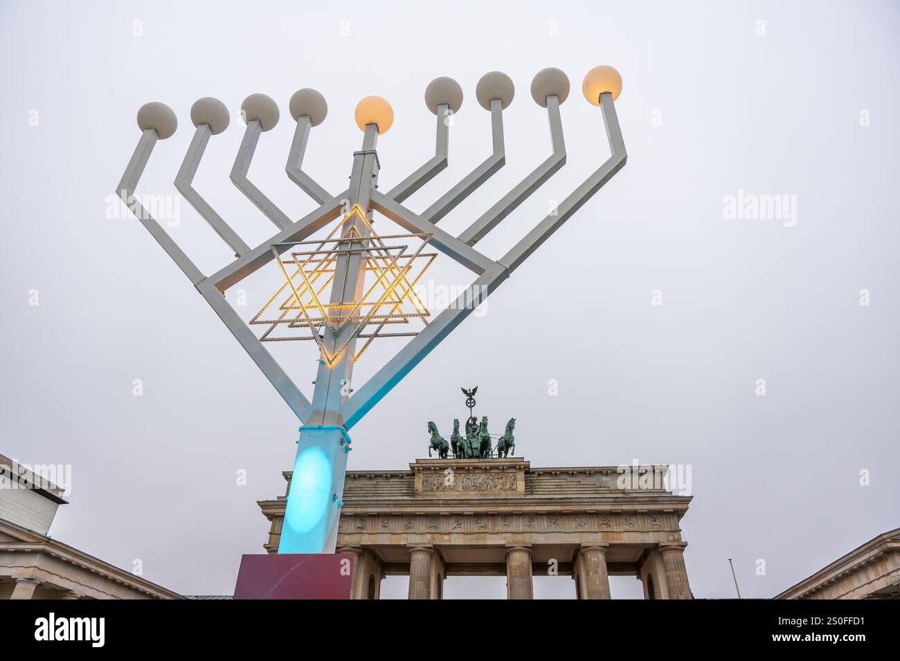 Vor dem Brandenburger Tor steht eine hohe beleuchtete Menora. Die Menora wird mit blauem Licht beleuchtet, was ihr ein festliches und festliches Aussehen verleiht. Stockfoto